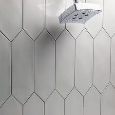 the shower head is attached to the tiled wall in this white bathroom with hexagonal tiles