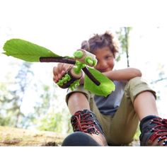 a young boy sitting on the ground holding a green plant with two leaves attached to it