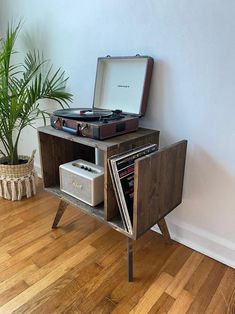 an old record player sits on top of a wooden table next to a potted plant