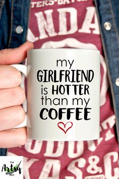 a person holding a coffee mug with the words my girlfriend is hotter than my coffee