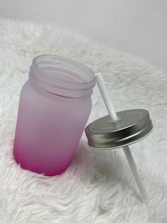 a glass jar with a straw on top of it sitting on a white fur rug