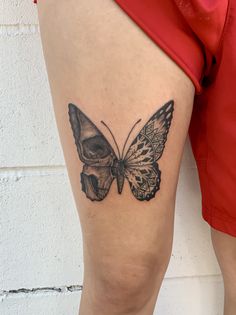 a woman's thigh with a butterfly tattoo on her left leg and skull in the middle