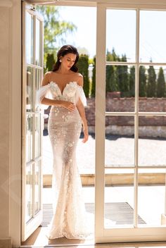 a woman standing in front of a door wearing a wedding dress