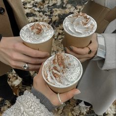 two women holding cups of hot chocolate drink with cinnamon sprinkles on them