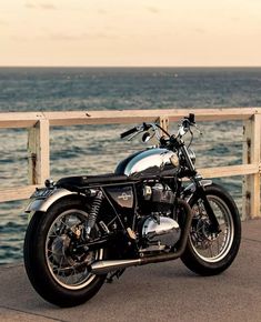 a black motorcycle parked on the side of a pier