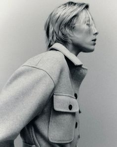 a black and white photo of a woman in a trench coat looking off to the side