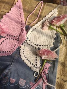 two crocheted pieces of clothing with pink flowers on the bottom and one piece of lace