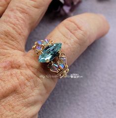 "Handmade Ring Swarovski Alexandrite Navette-Marquise Original Signature Design June Birthstone This ring seemed to take forever to create - not because of the design, but because of the color. The center stone is a Vintage Swarovski crystal in Alexandrite. Depending on the lighting, the color 'shifts\" between pale lavenders, blues and greens - though the pale green doesn't happen very often, because I believe it appears with a combination of different lightings. I finally settled on side cryst Plastic Ring, Swarovski Crystal Beads, Ring Color, June Birthstone, Crystal Ring, June Birth Stone, Crystal Rings, Pale Green, Signature Design