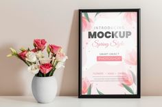 a vase filled with pink flowers next to a poster on a wall above a table