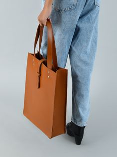 Embrace pure elegance with our artisan-crafted shopper tote. Woven from the very soul of buffalo leather, it doesn't just carry your belongings, but your style and confidence too. Its timeless brown shade, a silent nod to tradition, blends seamlessly with its contemporary design. Grasping the handles feels like shaking hands with timeless luxury. Revel in life's small moments of grandeur with every step, showcasing the world that you have an impeccable taste for both fashion and life's pleasures Waxed Canvas Bag, Duffel Bag Backpack, Bag Suitcase, Briefcase For Men, Brown Shades, Vegan Bags, Shopper Tote, Buffalo Leather, Leather Belts