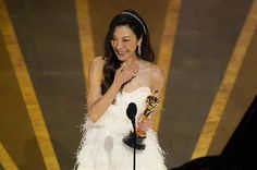 a woman in a white dress holding an award