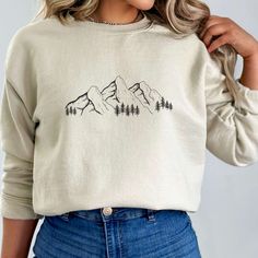 This stylish crewneck sweater is perfect for outdoor enthusiasts! It features a beautiful mountain landscape with evergreen trees. This simplistic mountain scape design reminds everyone of the outdoors and the beauty of nature. The high-quality fabric is soft and comfortable, making it ideal for those chilly days and nights. Whether you're camping, hiking, or just enjoying the natural world, this crewneck sweater is sure to become a favourite! More Information ♡ :   * Gildan Unisex Crewneck Swea Adventure Sweatshirt, Travel Hoodie, Camping Hoodie, Camper Shirt, Adventure Gifts, Hiking Shirt, Winter Nature, Hiking Shirts, Gifts For Nature Lovers