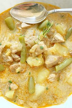 a white bowl filled with chicken and pineapple soup next to a spoon on top of a table