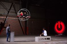 two people sitting on stools in front of a red sign and an upside down object