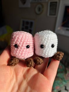 two tiny crocheted animals sitting on top of each other's fingers in front of a bed