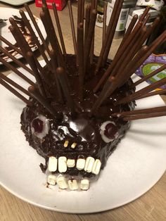 a chocolate cake with sticks sticking out of it's face on a white plate