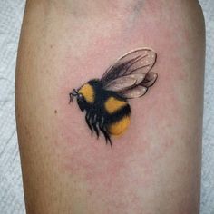 a small tattoo of a bum on the leg, it is yellow and black in color