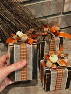 two wrapped gift boxes with pumpkins on them, one being held by a hand