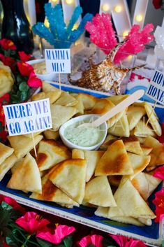 there are some pita chips and dip on the table with flowers in the background