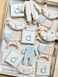 decorated cookies in the shape of baby's clothes and shoes are on a tray