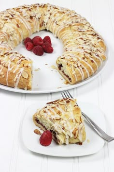 a white plate topped with a cake covered in frosting and raspberries