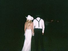 a man and woman standing in the dark with their back to each other, dressed in white