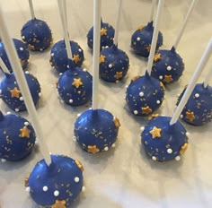 blue cake pops with white and gold sprinkles are arranged on a table