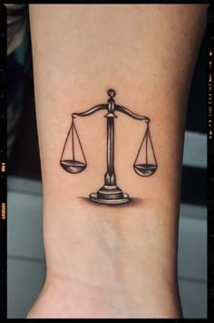 a black and white photo of a tattoo on the ankle that has an image of a scale