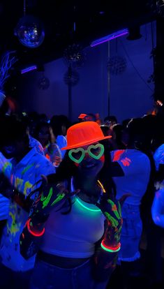 a woman wearing neon clothing and sunglasses in a dark room with disco balls hanging from the ceiling