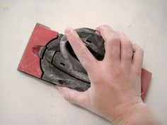 a hand holding a mouse on top of a white surface next to a red box