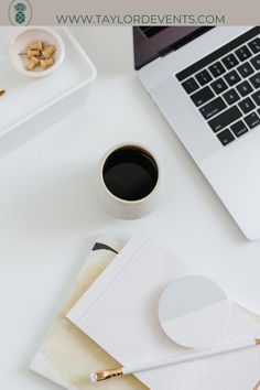 an open laptop computer sitting on top of a white desk next to a cup of coffee