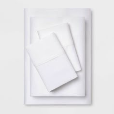 white sheets and pillowcases on top of each other in front of a white wall