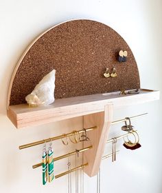 a wooden shelf with earring hooks and earrings hanging on it's sides next to a wall mounted jewelry rack