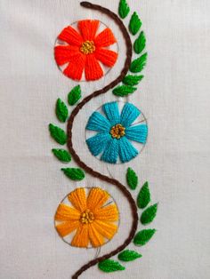 an embroidered piece with flowers and leaves on it