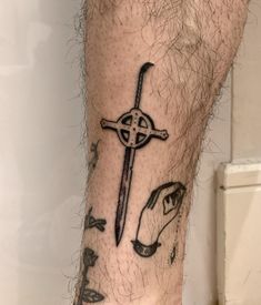 a man's foot with a cross tattoo on his left leg, and an arrow in the middle