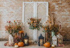 an outdoor fall wedding with pumpkins, flowers and lanterns on the ground in front of a brick wall