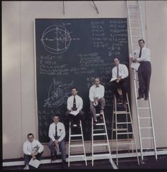 nasa scientist with their board of calculations, 1960's - men sitting on ladders in front of chalkboard