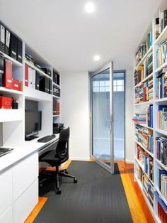 a home office with bookshelves, desk and computer on the far wall in front of glass doors