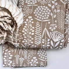 two pieces of fabric with flowers and leaves on them, one is brown and the other is white