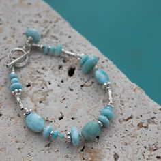 Lovely simple Larimar and Thai Hill tribe Silver Beaded Bracelet to complement any Larimar Lovers wardrobe :)  Length of bracelet - 19.5cm  Larimar - is the embodiment of the tranquil Sea and Sky energies. Its soft, soothing blues and calming turquoise is streaked with white patterns that resemble sunlight dancing beneath Caribbean waters. It brings the ancient wisdom of Atlantis and the healing power of dolphins to harmonize the body and soul. Larimar is one of the cardinal Water element stones Turquoise Larimar Natural Stone Bracelets, Adjustable Turquoise Larimar Beaded Bracelets, Handmade Adjustable Larimar Bracelets, Silver Beaded Bracelet, Hill Tribe Silver, Emotional Body, Water Element, Silver Bead Bracelet, Healing Power