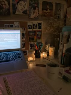 an open laptop computer sitting on top of a desk next to a cup and candles