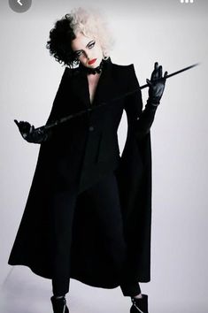 a woman dressed in black holding a wand