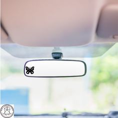 the rear view mirror has a butterfly sticker on it's side window and is hanging from the ceiling