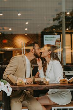 a man and woman sitting at a table kissing