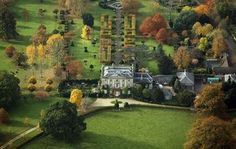 an aerial view of a large house surrounded by trees and grass in the fall season