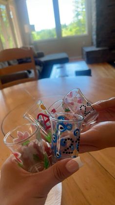 someone is holding up some plastic cups with letters and numbers on them in front of a table