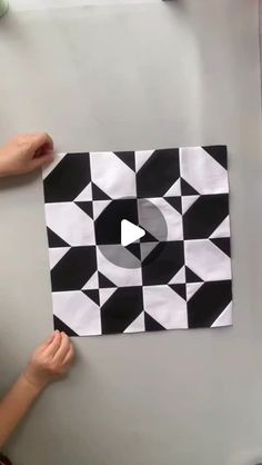 someone holding up a piece of paper with black and white designs on it