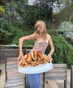 a woman holding a tray full of hot dogs