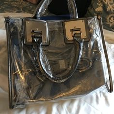 This satchel and tote handbag is 2-in-1. It's a transparent satchel tote with a complimentary removable shoulder bag. This bag is awesome! If you love chic bags, this is the perfect bag for you!

2-day processing. Shipped in 4-7 days. Trendy Clear Shoulder Bag Satchel, Trendy Crossbody Satchel With Clear Strap, Clear Satchel Bag For Travel, Trendy Clear Satchel For Travel, Trendy Large Capacity Clear Bag, Trendy Clear Travel Satchel, Clear Tote Shoulder Bag With Removable Pouch, Clear Shoulder Bag With Removable Pouch For Shopping, Trendy Shoulder Satchel With Clear Strap