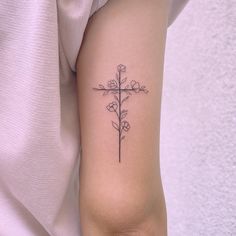 a cross tattoo with flowers on the arm